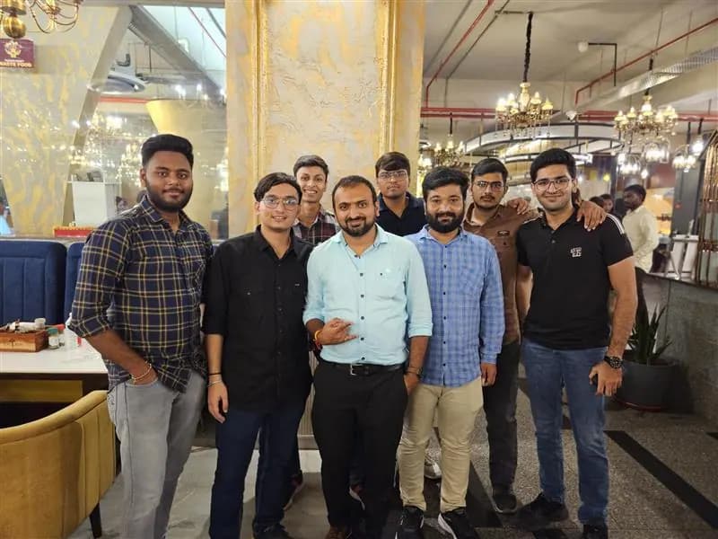 Team members at a group dinner in a restaurant lit by chandeliers