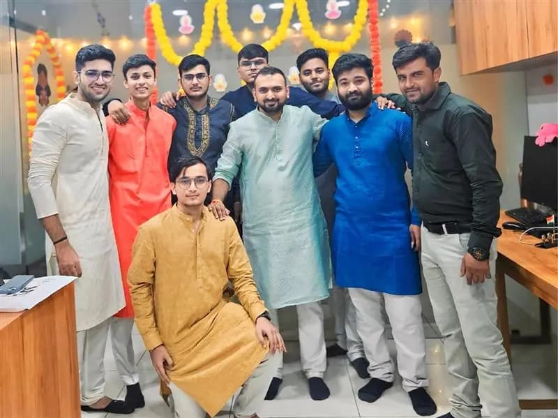 Colleagues in traditional dress beside marigold decorations at the office festival celebration