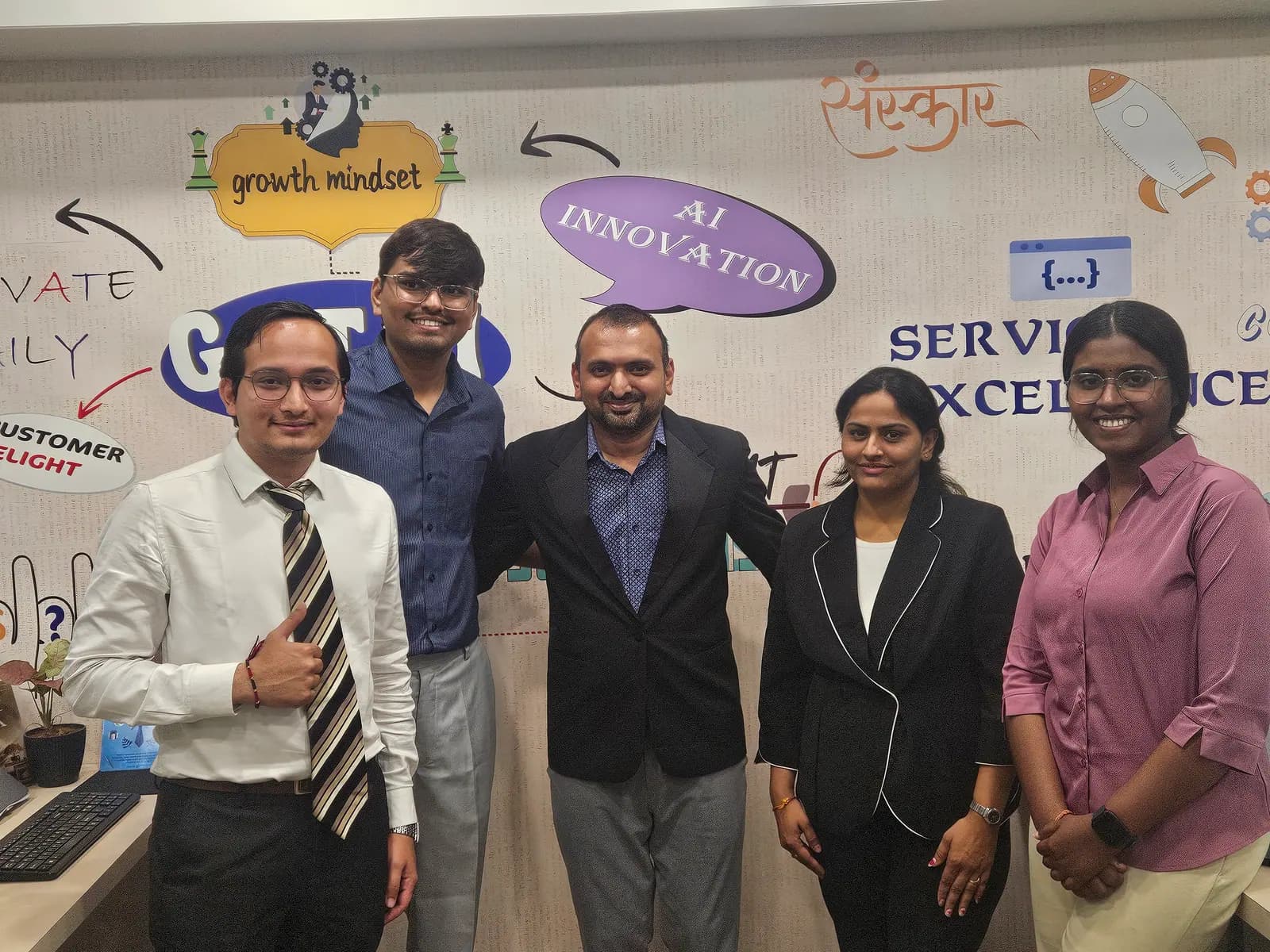 Five team members standing in front of the office wall painted with 'Growth Mindset' and 'AI Innovation'
